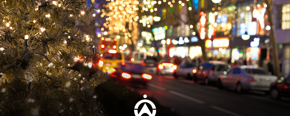 A festive city street with Christmas lights and blurred traffic at night.
