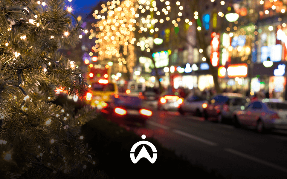 A festive city street with Christmas lights and blurred traffic at night.