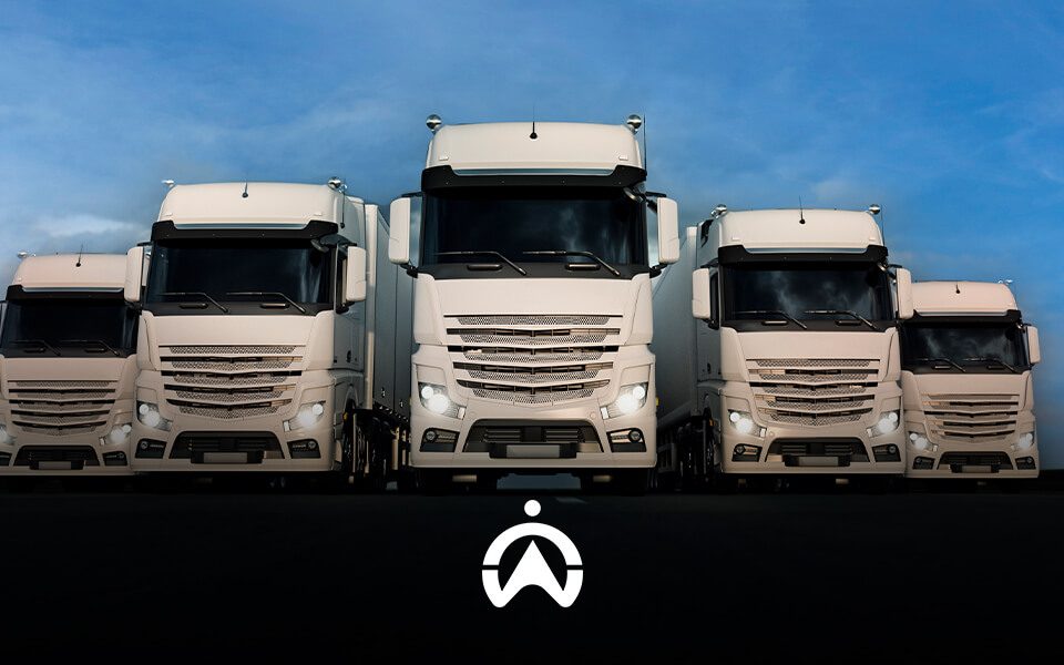 Five large, white trucks are lined up against a blue sky, with a logo visible at the bottom center of the image.