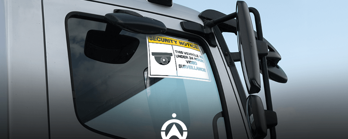 Close-up of a vehicle window displaying a security notice warning of 24-hour video surveillance.