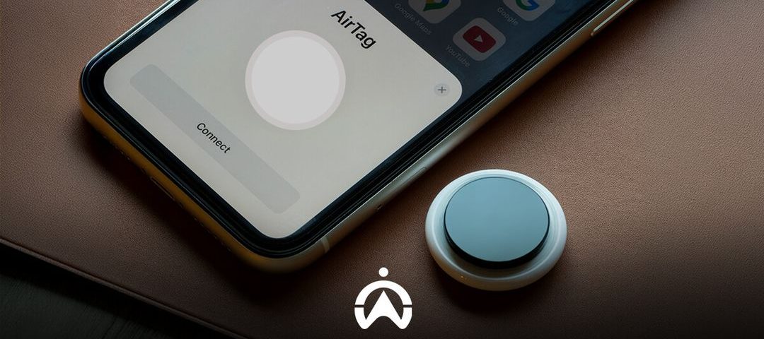 An iPhone displaying the "AirTag" setup screen next to an AirTag device, set on a leather surface.