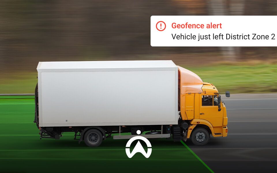 A yellow truck on a road, accompanied by a geofence alert indicating it has exited District Zone 2. Green zone markings visible.