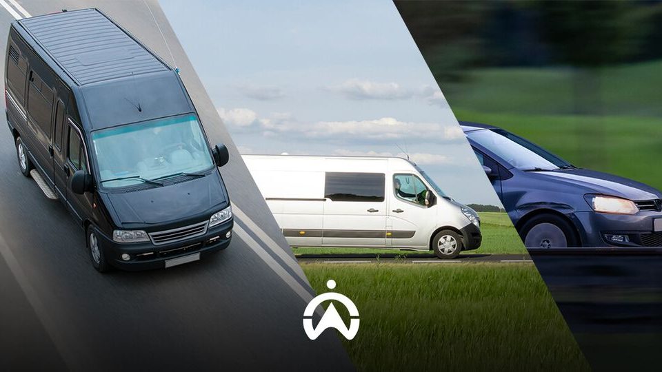 Three delivery vans on the road: a black van on the left, a white van in the center, and a dark blue car on the right.